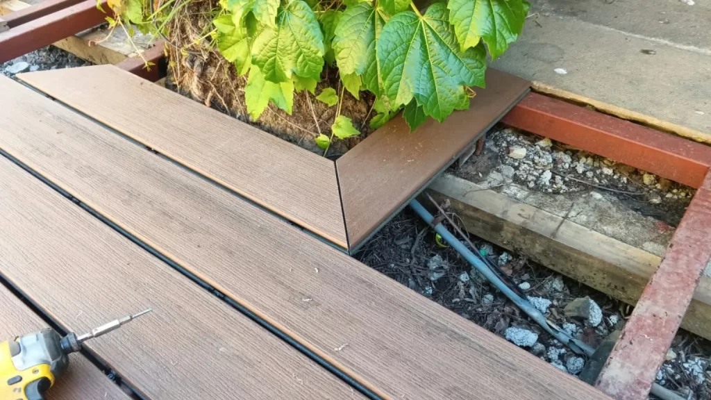 Tablas WPC en proceso de instalación junto a una jardinera